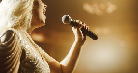 Close Up Portrait of a Blonde Musician Using a Microphone to Sing a Powerful Pop Song in a...