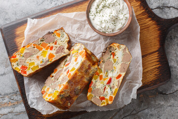 Liver casserole with vegetables, herbs and eggs close-up on a wooden board on the table. Horizontal top view from above