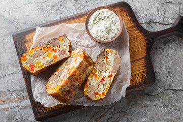 Festive baked pie with chicken liver, carrots, peppers, herbs and eggs close-up on a wooden board on the table. Horizontal top view from above