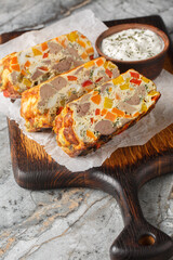Chicken liver eggs vegetables casserole sliced ​​close-up on wooden board on table. Vertical