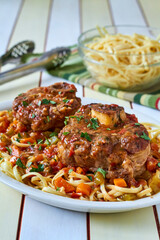 osso bucco served on pasta topped with a vegetable ragout gravy