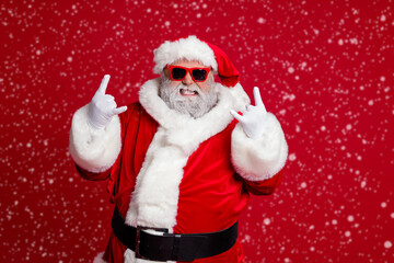 Portrait of attractive crazy Santa showing horn symbol having fun newyear occasion isolated over bright red color background