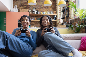 Female friends playing video game sitting on floor in loft apartment