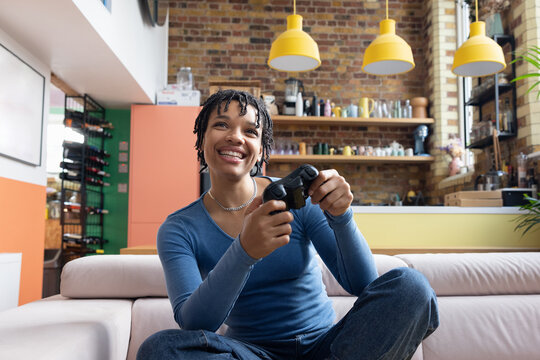 Young adult female playing video game sitting on floor in loft apartment