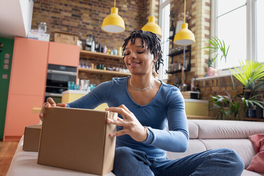 Happy young African American opening an online order at home
