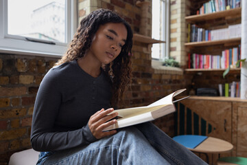 Young black woman reading a book at home