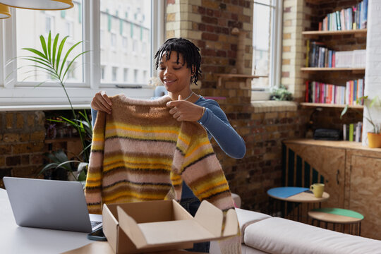 Young African American female vintage fashion business owner packing an online order to ship