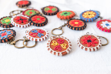 A collection of colorful terracotta keychains with unique embroidered designs, perfect for boho-inspired home decor or as personalized gifts for any occasion