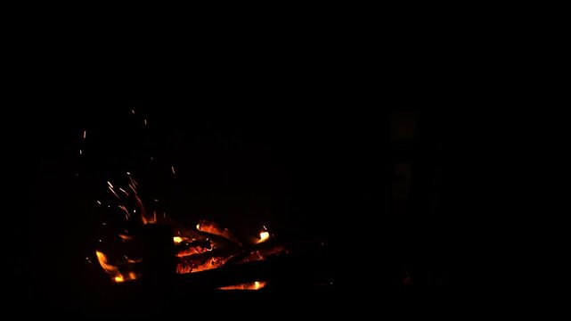 The fireplace in the house burns like a bonfire on natural wood and branches from the forest. The fire is actively burning, a tree falls and flares up