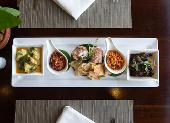 Top view of a  Sri Lankan breakfast platter with pittu, parata, pol sambol, lunu miris, fish ambulthiyal and kiri maalu fish coconut curry on a table