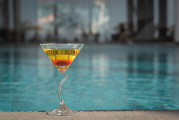Aperol Spritz Cocktail Glass by a swimming pool
