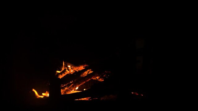 The fireplace in the house burns like a bonfire on natural wood and branches from the forest. The fire is actively burning, a tree falls and flares up