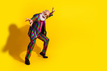 Eccentric elderly gentleman in a vibrant striped suit dancing joyfully against a bold yellow backdrop