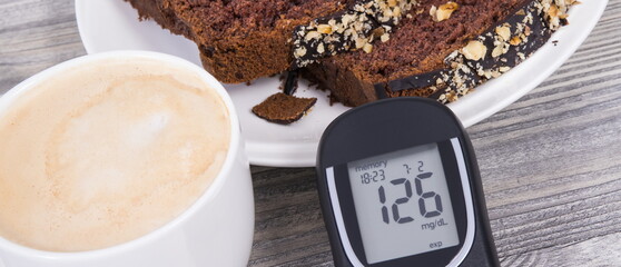 Glucose meter with high result sugar level, sweet chocolate cake and cup of coffee with milk. Nutrition during diabetes