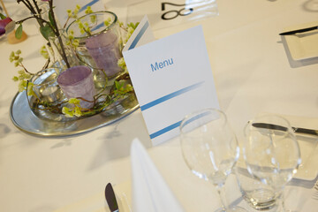 Elegant dining table setup features menu and floral arrangements for special occasion in a bright venue