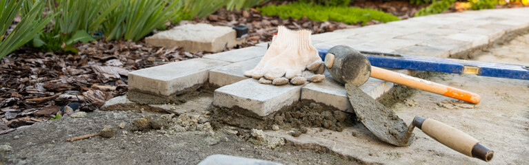 Banner, Laying paving stones on cement mortar. Laying a garden path made of tiles. Self-laying of concrete paving slabs in the courtyard of the house. do it yourself. DIY