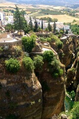 Andalusian village perched on a clifftop overlooking a deep gorge. The whitewashed buildings and lush greenery in rugged, rocky landscape. Essence of Spain's natural beauty and rich cultural heritage