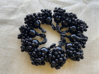 A captivating arrangement of black beads in varying sizes, meticulously assembled into a circular...