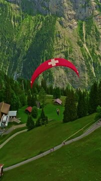 Aerial view beautiful of Paraglider flying with a picture of the Swiss flag on it in the alpine mountains in Switzerland