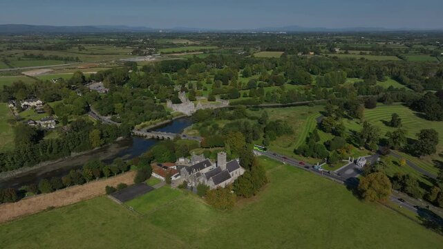 Augustinian Friary, Adare, County Limerick, Ireland, September 2024. Drone orbits clockwise in a panoramic overview showcasing the winding River Maigue alongside forested riverbanks and grassy fields.