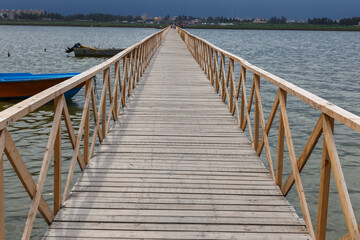 Obraz premium Wooden walkway leads to the Caspian Sea in Iran with boats and cityscape visible