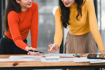 Fototapeta premium Collaborative women discussing business strategies with charts and documents. Engaged in productive meeting, showcasing teamwork and creativity
