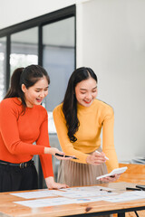 Creative collaboration between two women in colorful sweaters, engaged in brainstorming session at modern workspace. Their expressions reflect enthusiasm and teamwork