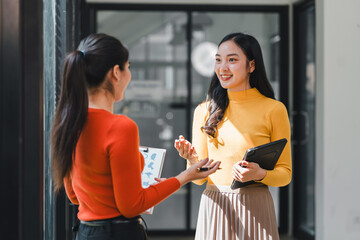 Engaged conversation between two women in modern office setting, showcasing collaboration and professionalism. woman in yellow exudes confidence while discussing ideas