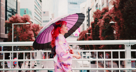 City, umbrella and happy woman in kimono walking on bridge with smile, morning travel or sightseeing. Fashion, pink style and Japanese girl in traditional clothes, parasol or culture on urban commute © peopleimages.com