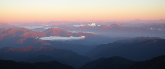 Obraz premium Sunset over mountain range with layers of mist