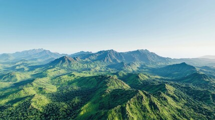 Fototapeta premium Aerial view captures lush green mountains beneath a clear blue sky, presenting a stunning green landscape filled with vibrant foliage and open space for creative uses.