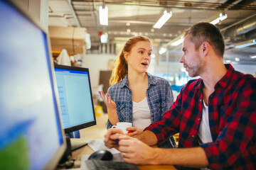 Young man and woman using a computer while working in a printing press office