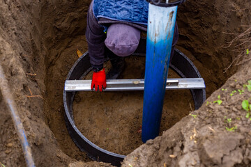 Workers install a water intake unit in a well. Installation of the walls of the pumping station...