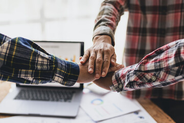 Coworkers gather around and hold hands in the workplace. Concept of cooperation with friends and teamwork.