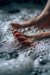 Fototapeta premium Close-Up of Feet Relaxing in a Bubble-Filled Bath