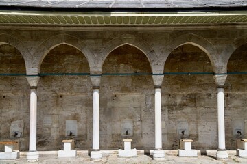 Fototapeta premium Ablution fountains of the historic Kilic Ali Pasha Mosque, with an arched roof structure supported by columns.