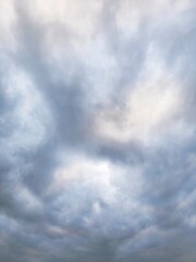 the grey overcast sky. A sweeping pattern of clouds evolving as an intricate background pattern. Cloudscape scenery, overcast weather.