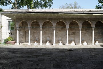 Obraz premium Ablution fountains of the historic Kilic Ali Pasha Mosque, with an arched roof structure supported by columns. 