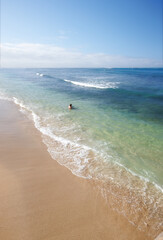 Swimming, sky and person on beach with waves, sand and tropical holiday for travel getaway in nature. Calm, ocean and tourist in water for island vacation, outdoor adventure and relax in Indonesia