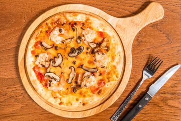 Black Truffle Mushroom and Shrimp Pizza served on wooden board with knife and fork isolated on table top view of italian cousin