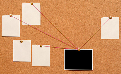 Blank paper notes and an empty photo are pinned to a cork board. The concept of detective investigation.