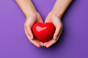 Obraz premium Hands holding a red heart on purple background