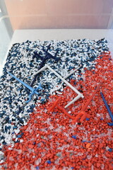 Recycled crushed plastic. Recycling and reuse of plastic. The problem of environmental pollution. Ecology and innovations. Various types of plastic in red and blue.