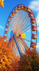 Fototapeta premium Vibrant Ferris wheel towering against azure sky, framed by golden autumn foliage. Colorful gondolas catch sunlight, creating a festive atmosphere in the fall fairground.