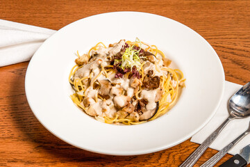 Chicken Spaghetti with Porcini Cream Sauce served in plate isolated on wooden table side view of italian cousin