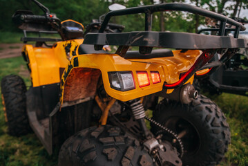 quad bikes stand on the river bank in the forest against the backdrop of a beautiful evening sky and water. headlights wheels muffler close-up © Julia Suhareva