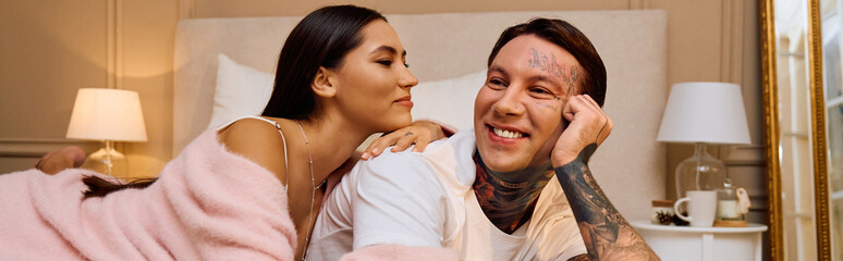 Loving couple relaxes together, enjoying laughter and closeness in their warmly lit bedroom.