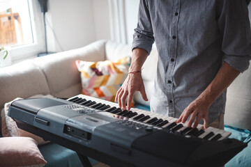 Musician's hands actively playing a digital keyboard, blending focus and creativity in a modern home setting with soft lighting and minimalist decor