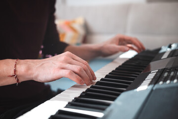 Obraz premium Close-up of a digital keyboard with a hand playing a melody, illuminated by soft natural light. The detailed controls and keys evoke creativity and musical exploration