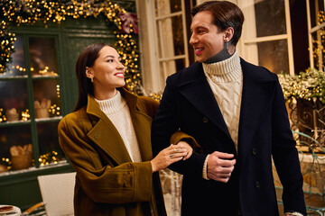 A couple smiles warmly, walking arm in arm in a beautifully decorated space.